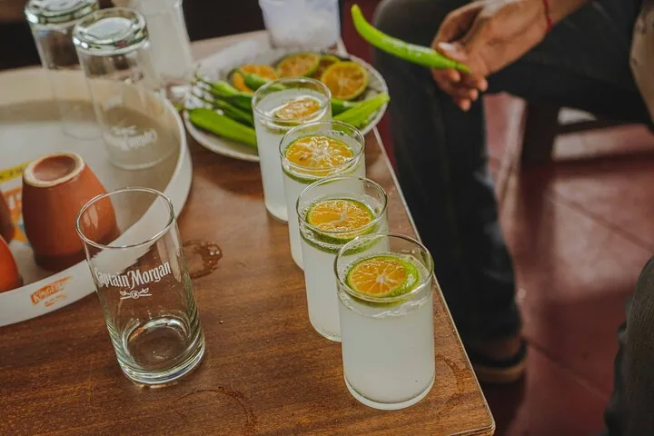 Four glasses of lemonade with a slice of lime on a wooden table.